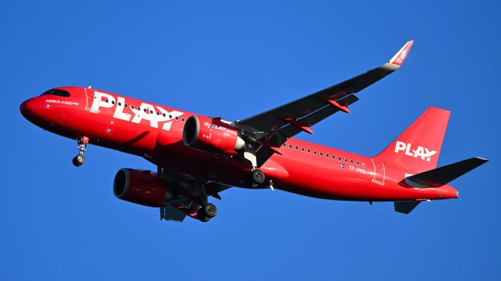 Flying Play Airlines jet with blue sky, emphasizing safety regulations.